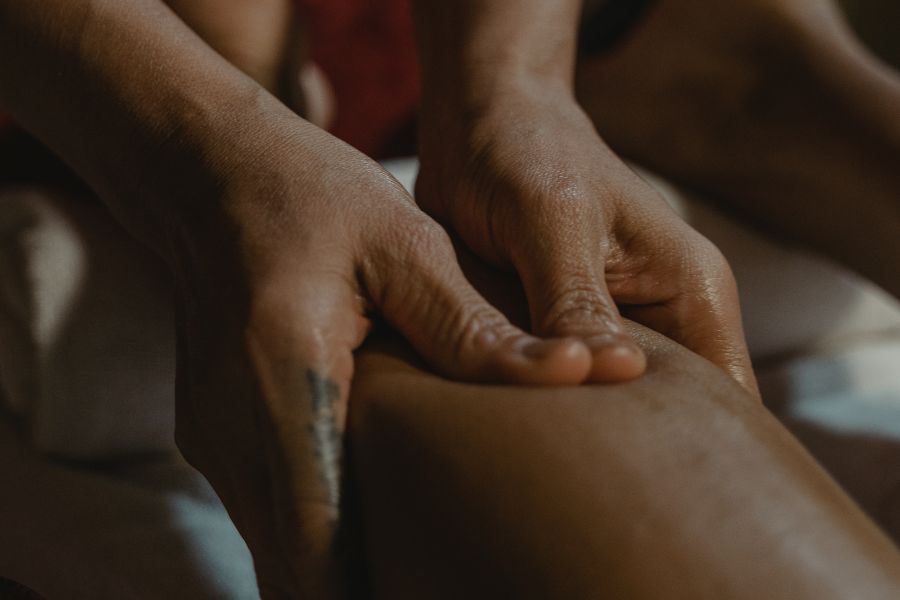 Close-up of therapist's hands giving deep tissue leg massage for pain relief at spa.